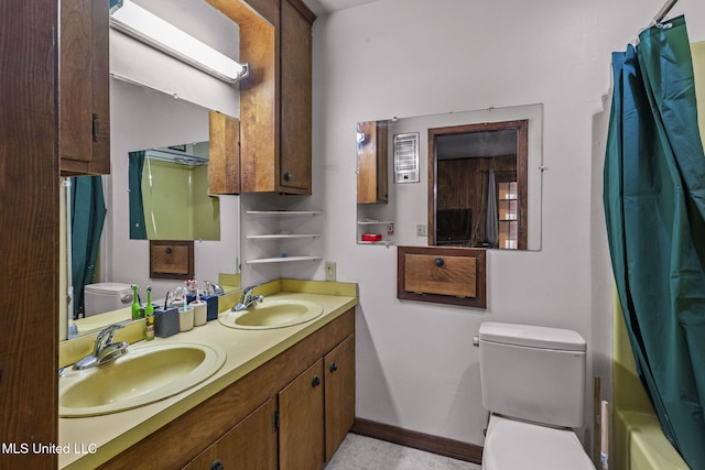 bathroom featuring toilet, double vanity, baseboards, and a sink