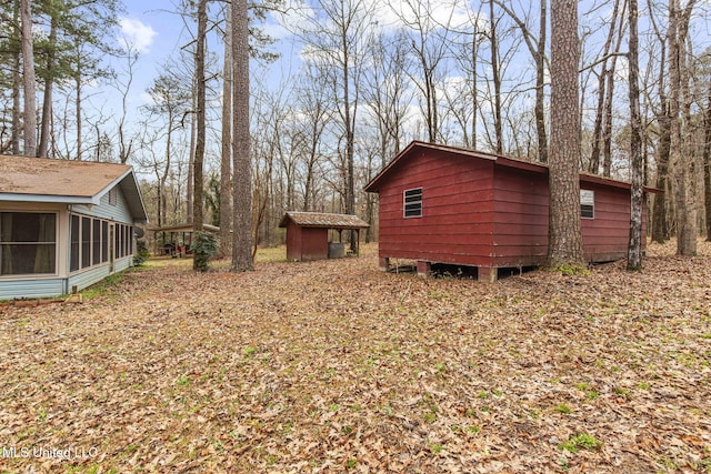 view of yard with an outbuilding, a shed, and a sunroom