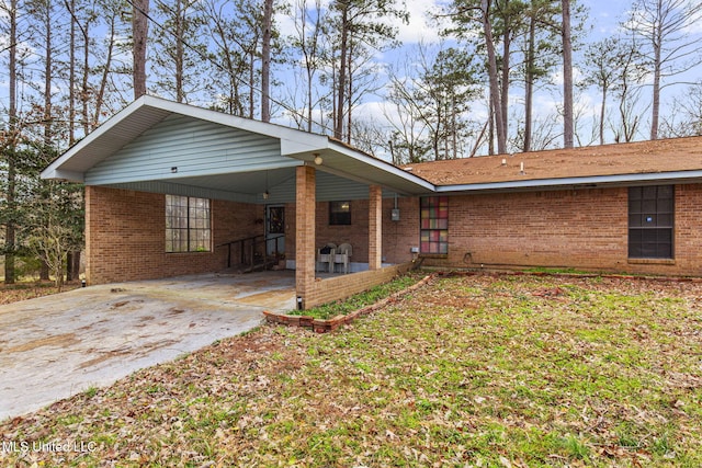 back of property with a carport, concrete driveway, and brick siding