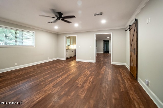 unfurnished bedroom featuring a barn door, crown molding, dark wood-style floors, a sink, and recessed lighting