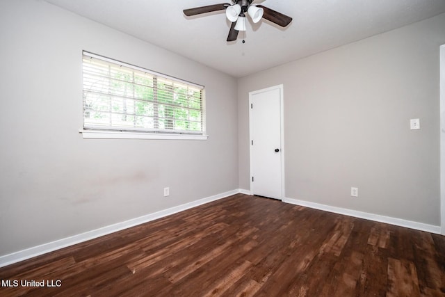 empty room with dark wood-style floors, baseboards, and a ceiling fan