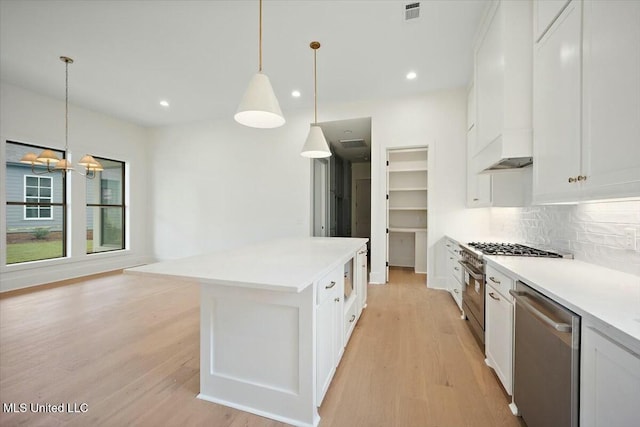 kitchen with light wood-style flooring, tasteful backsplash, visible vents, appliances with stainless steel finishes, and custom range hood
