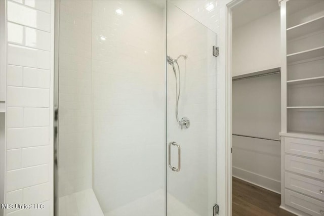 bathroom with a shower stall and wood finished floors