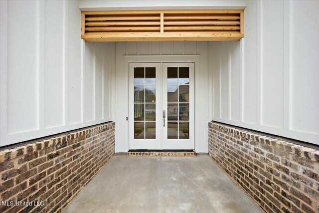 view of exterior entry with board and batten siding and french doors
