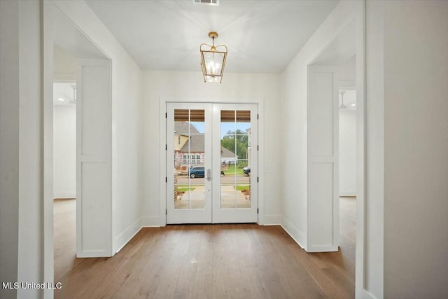 doorway featuring baseboards, a chandelier, french doors, visible vents, and wood finished floors