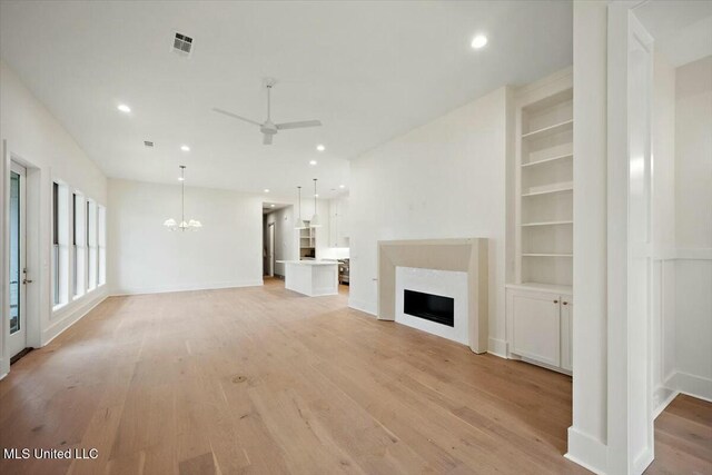 unfurnished living room featuring visible vents, light wood-type flooring, recessed lighting, and ceiling fan with notable chandelier
