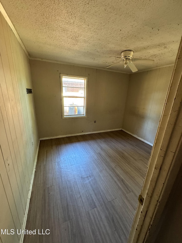 unfurnished room featuring ceiling fan, dark hardwood / wood-style flooring, and wooden walls