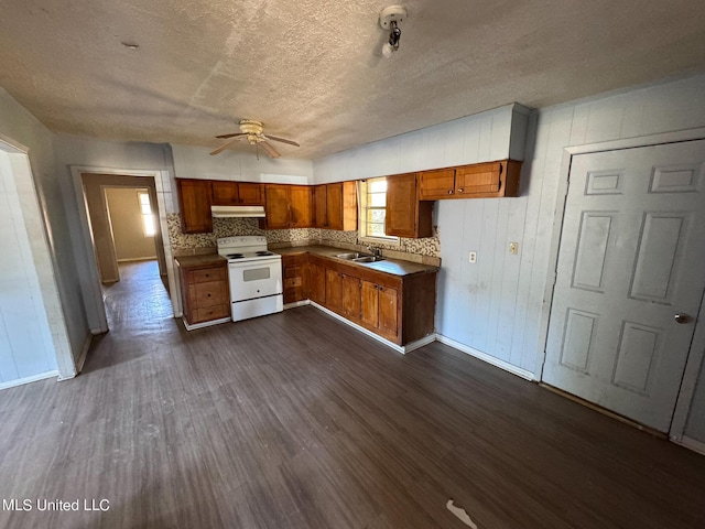 306 Hillcrest St, Carthage, MS 39051 - kitchen with white electric range oven, under cabinet range hood, brown cabinetry, a sink, and baseboards