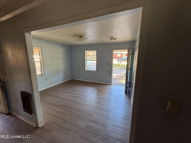 unfurnished living room featuring hardwood / wood-style floors, a textured ceiling, and wooden walls