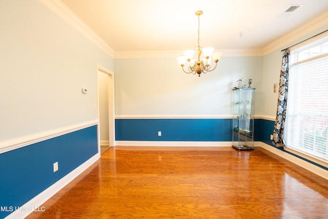 unfurnished room featuring an inviting chandelier, crown molding, and hardwood / wood-style flooring