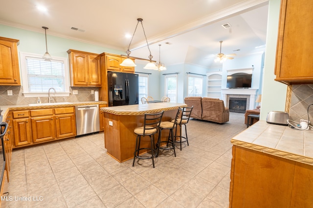 kitchen with black refrigerator with ice dispenser, ceiling fan, backsplash, a kitchen island, and stainless steel dishwasher