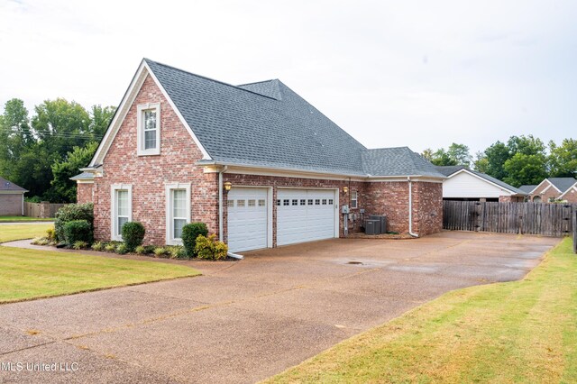 890 Lindsey Cv, Hernando, MS 38632 - view of side of property featuring concrete driveway, brick siding, roof with shingles, central AC unit, and a garage