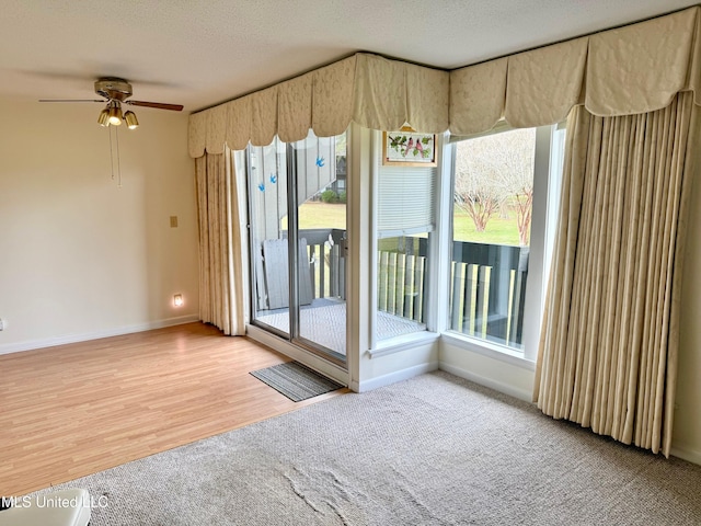 interior space featuring ceiling fan, a textured ceiling, baseboards, and wood finished floors