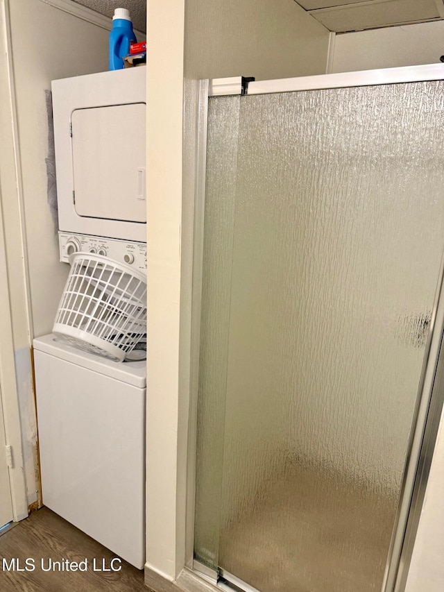 laundry area featuring stacked washer and dryer, laundry area, and wood finished floors