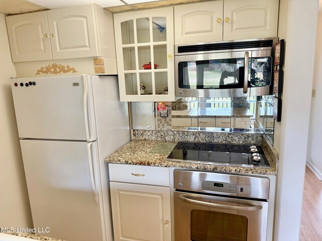 kitchen with glass insert cabinets, tasteful backsplash, appliances with stainless steel finishes, and white cabinets