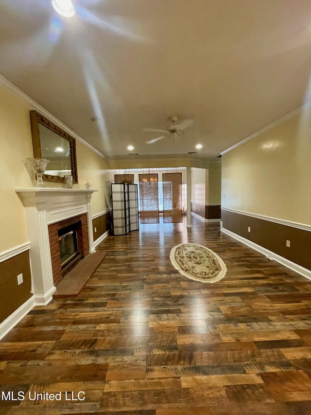 unfurnished living room featuring a fireplace, ornamental molding, dark hardwood / wood-style floors, and ceiling fan