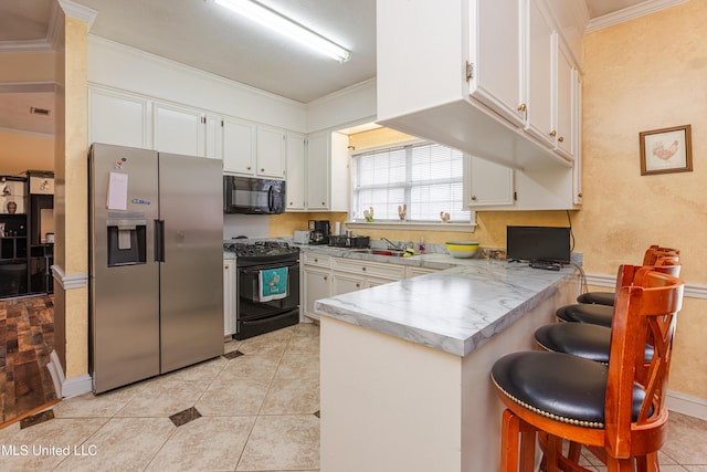 kitchen with white cabinetry, black appliances, kitchen peninsula, and a kitchen bar