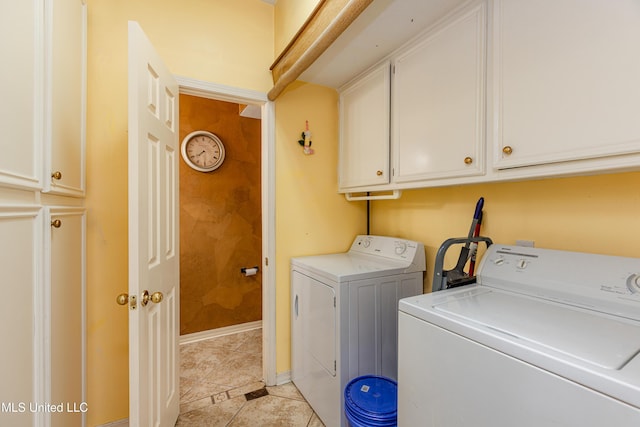 laundry room with cabinets, light tile patterned floors, and washing machine and clothes dryer