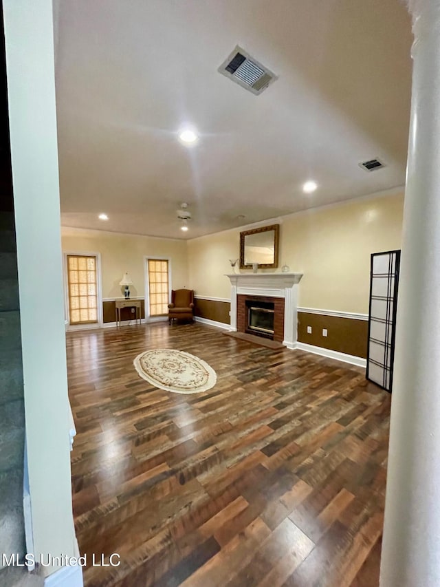 unfurnished living room featuring dark wood-type flooring, a fireplace, and ornate columns