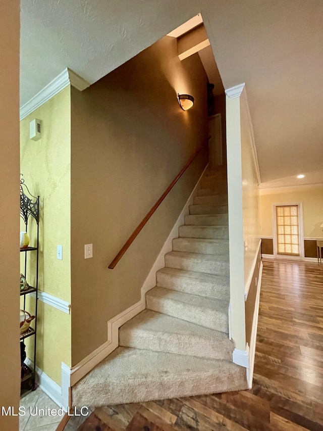 stairs featuring crown molding and hardwood / wood-style floors