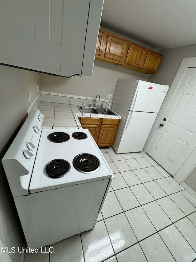 1607 Resca De La Palma St, Pascagoula, MS 39567 - kitchen with white appliances, a sink, tile countertops, brown cabinetry, and light tile patterned floors