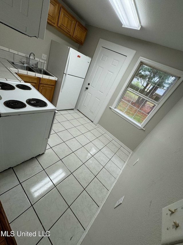 1607 Resca De La Palma St, Pascagoula, MS 39567 - kitchen featuring tile countertops, white appliances, brown cabinets, light tile patterned floors, and a sink
