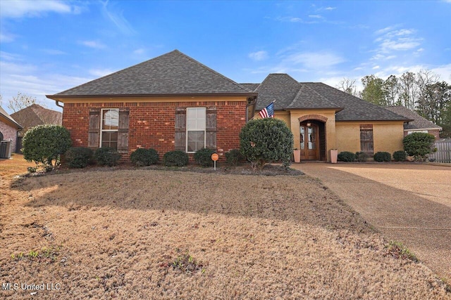 view of front of property featuring central air condition unit, a shingled roof, and brick siding