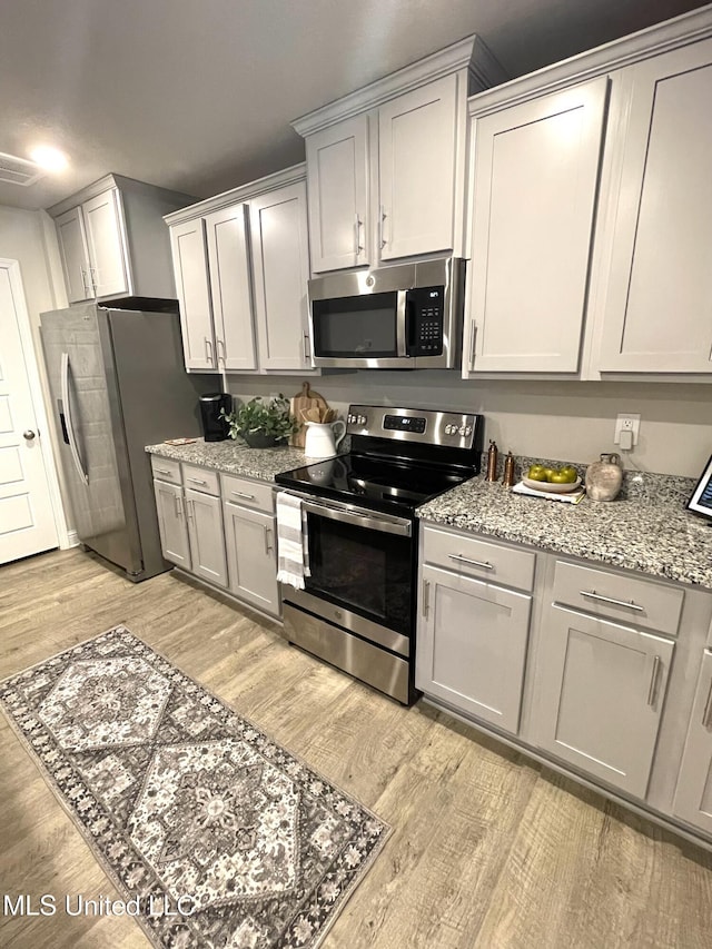 5438 Leeds Ln, Biloxi, MS 39532 - kitchen with visible vents, light wood finished floors, appliances with stainless steel finishes, and light stone countertops