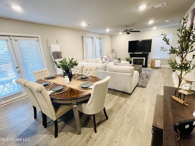 5438 Leeds Ln, Biloxi, MS 39532 - dining area with light wood finished floors, a glass covered fireplace, a ceiling fan, baseboards, and visible vents