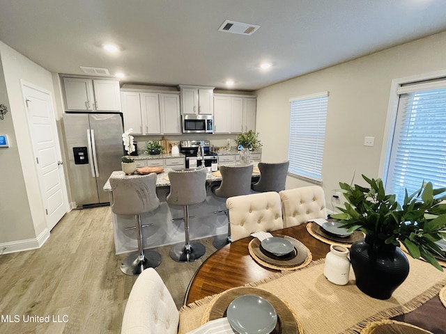 5438 Leeds Ln, Biloxi, MS 39532 - kitchen featuring a kitchen breakfast bar, visible vents, light wood-type flooring, light stone counters, and stainless steel appliances