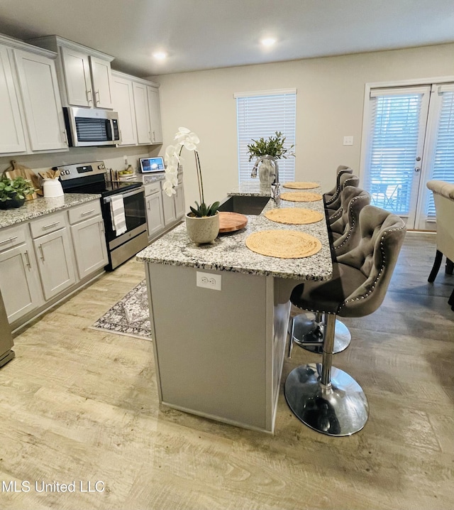 5438 Leeds Ln, Biloxi, MS 39532 - kitchen with light stone countertops, light wood finished floors, a kitchen breakfast bar, stainless steel appliances, and a kitchen island