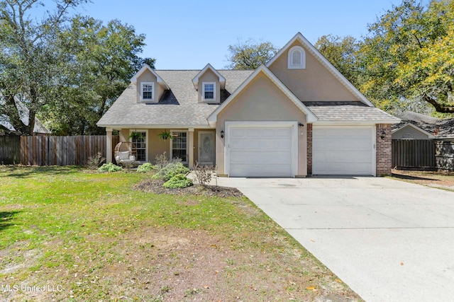 view of front of home with fence, a front yard, stucco siding, a garage, and driveway