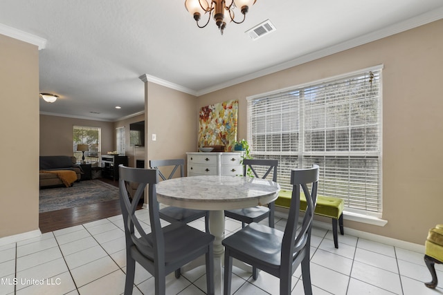 dining room with light tile patterned floors, visible vents, plenty of natural light, ornamental molding, and a notable chandelier