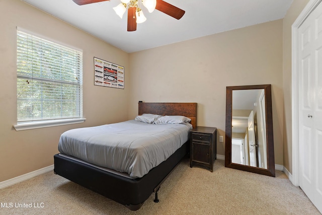 bedroom featuring light carpet, a ceiling fan, and baseboards