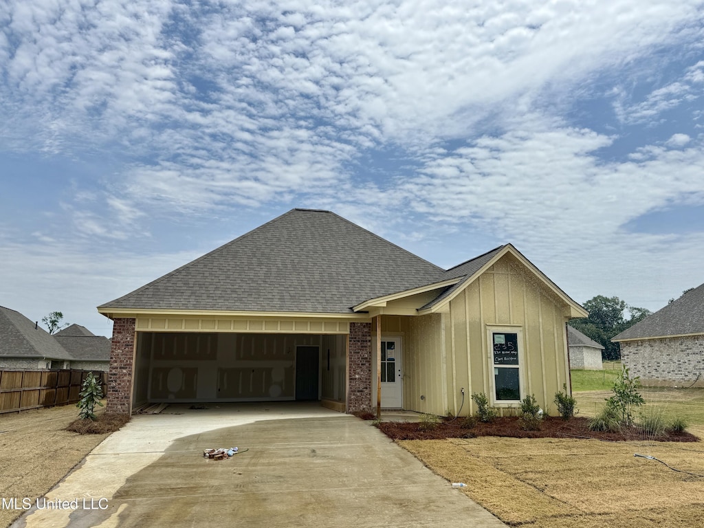 330 Willow Way, Canton, MS 39046 - view of front of house featuring board and batten siding, an attached garage, driveway, a shingled roof, and brick siding