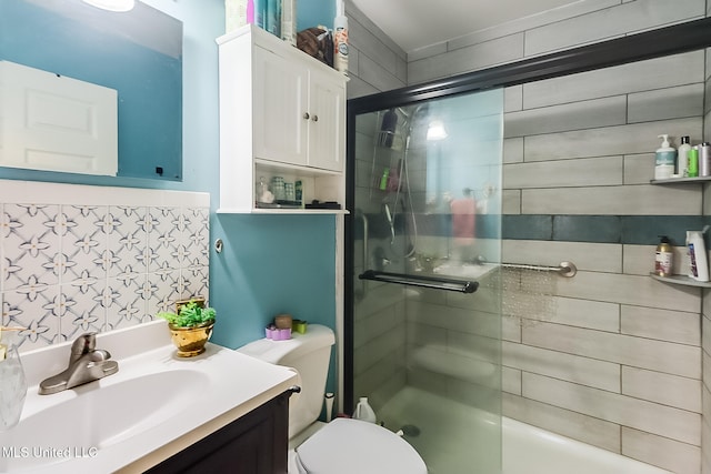 bathroom featuring toilet, vanity, tile walls, and a shower with door