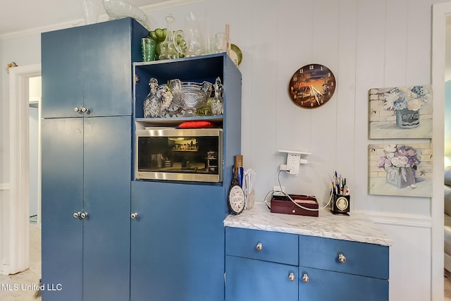 bar with blue cabinets, light stone countertops, and ornamental molding