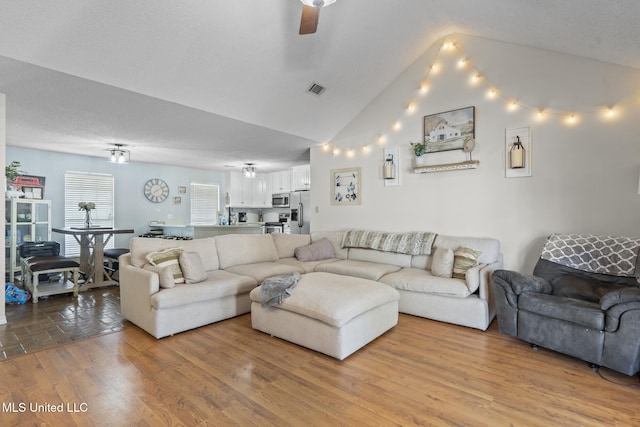 living room with ceiling fan, lofted ceiling, and light wood-type flooring