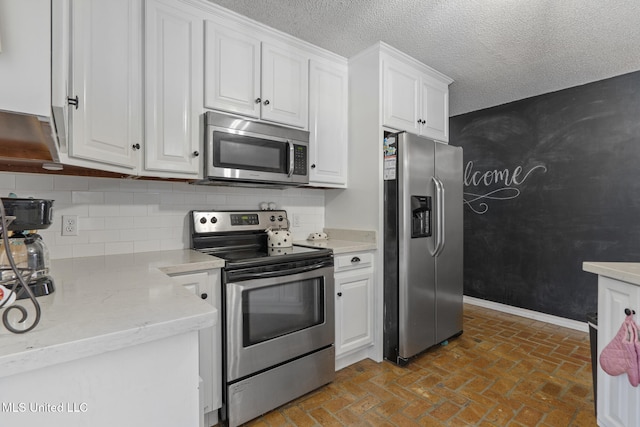 kitchen featuring tasteful backsplash, white cabinetry, appliances with stainless steel finishes, and a textured ceiling