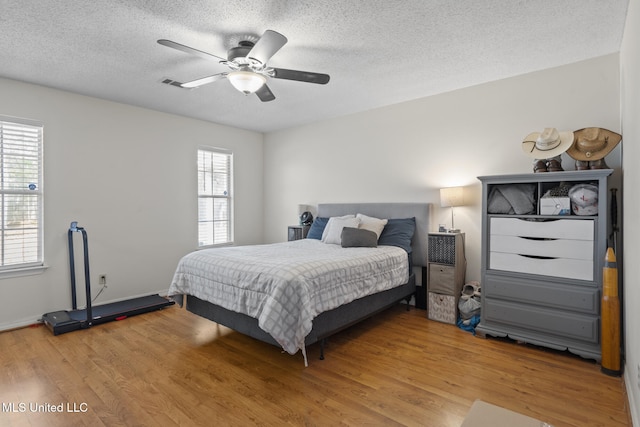 bedroom with hardwood / wood-style floors, a textured ceiling, and ceiling fan