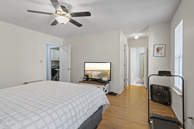 bedroom featuring ceiling fan, a textured ceiling, and light wood-type flooring