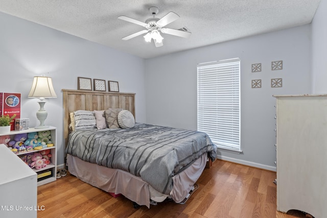 bedroom featuring ceiling fan, hardwood / wood-style flooring, and a textured ceiling