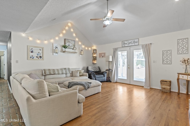 living room with ceiling fan, hardwood / wood-style floors, a textured ceiling, vaulted ceiling, and french doors