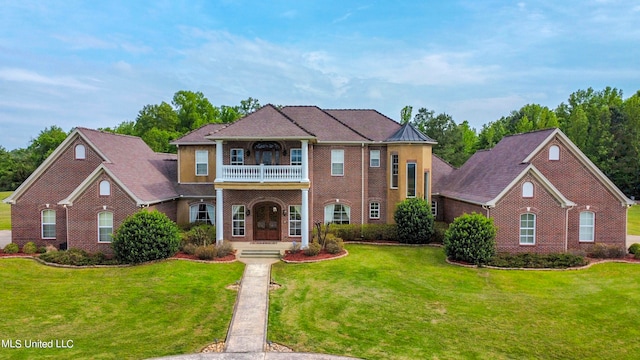 view of front of property featuring a balcony, a front yard, and covered porch