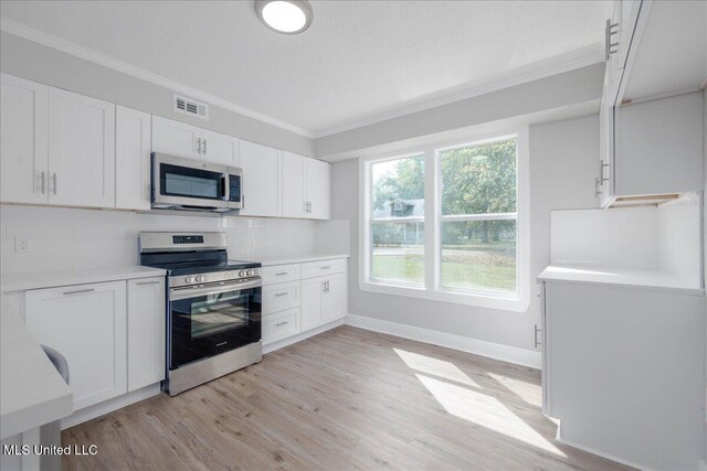 250 1st St, Webb, MS 38966 - kitchen featuring appliances with stainless steel finishes, light wood-style flooring, decorative backsplash, crown molding, and white cabinets