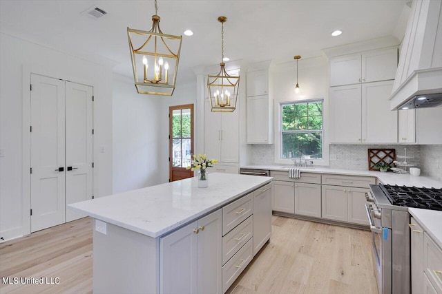 kitchen featuring a healthy amount of sunlight, decorative light fixtures, high end stove, and a kitchen island