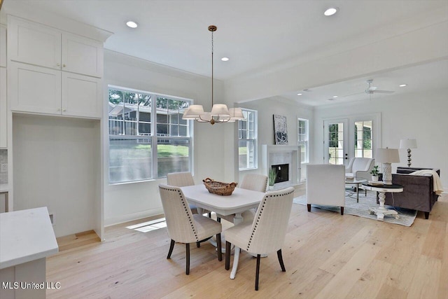 dining area with crown molding, light wood-type flooring, and ceiling fan with notable chandelier