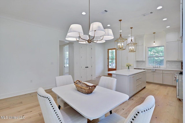 dining room featuring crown molding, light hardwood / wood-style flooring, and a healthy amount of sunlight