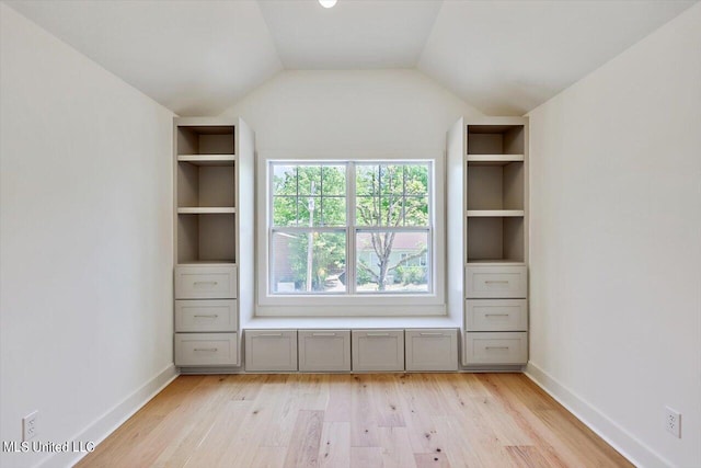 unfurnished bedroom with vaulted ceiling and light wood-type flooring