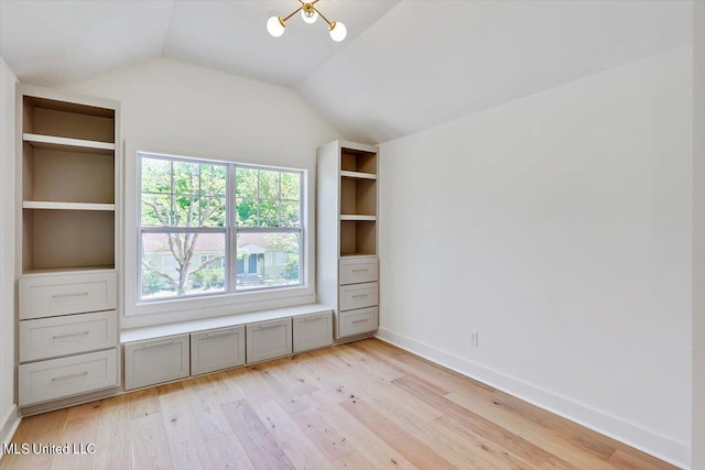 unfurnished bedroom with vaulted ceiling, light hardwood / wood-style flooring, and an inviting chandelier